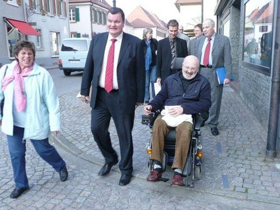 Bürgermeister Matthias Guderjan, Cornelia Wangler und Winfried Höhemann testen das abgeschliffene Natursteinpflaster